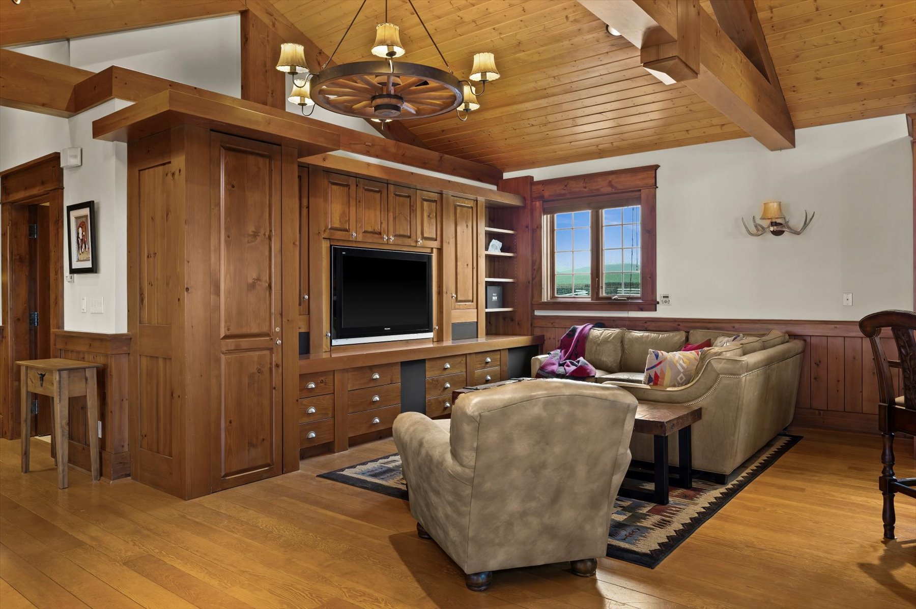 Den with leather sectional, built-in media wall and antler sconces