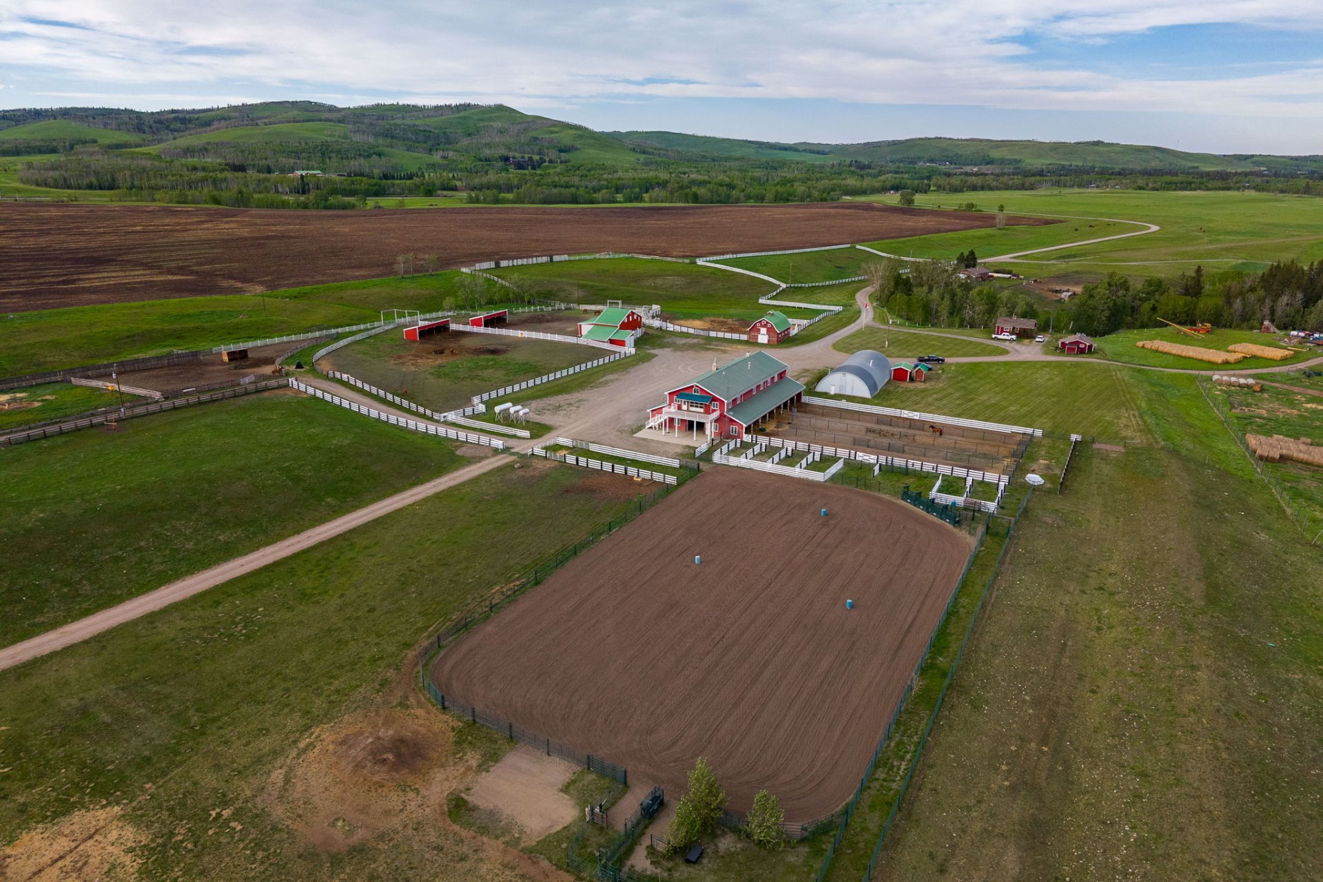 Aerial of the equestrian complex with arena, barns, and foothills beyond