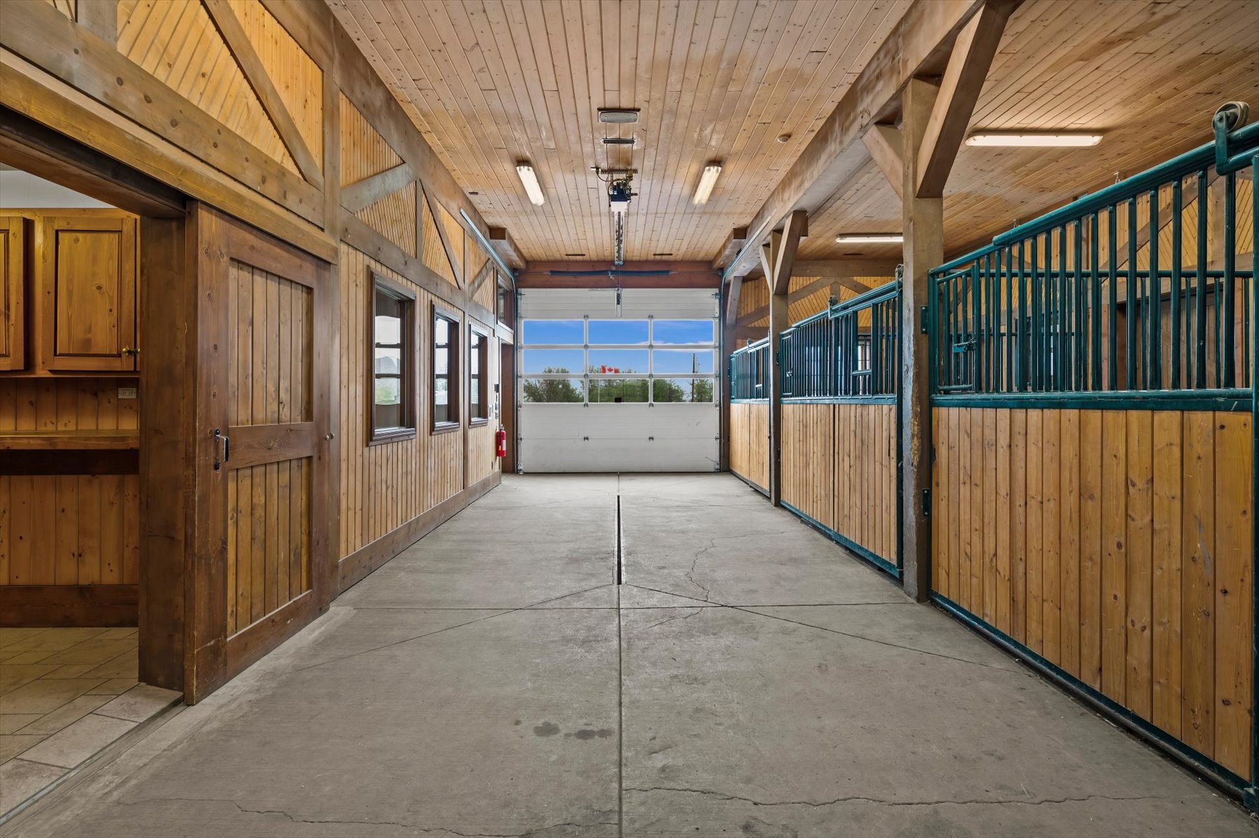 Timber-frame stall aisle with green steel grilles and tongue-and-groove pine