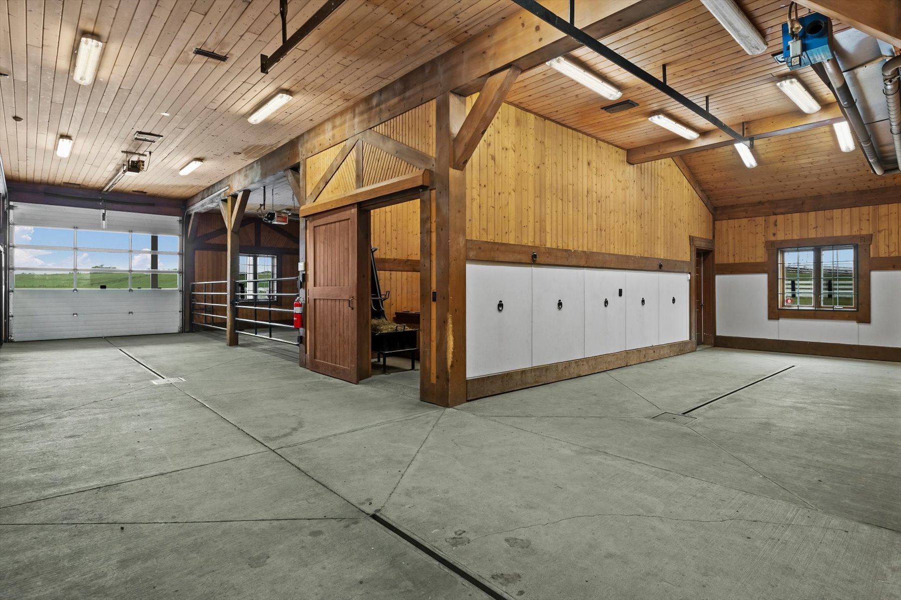 Open breezeway inside the barn with overhead glass door to pasture