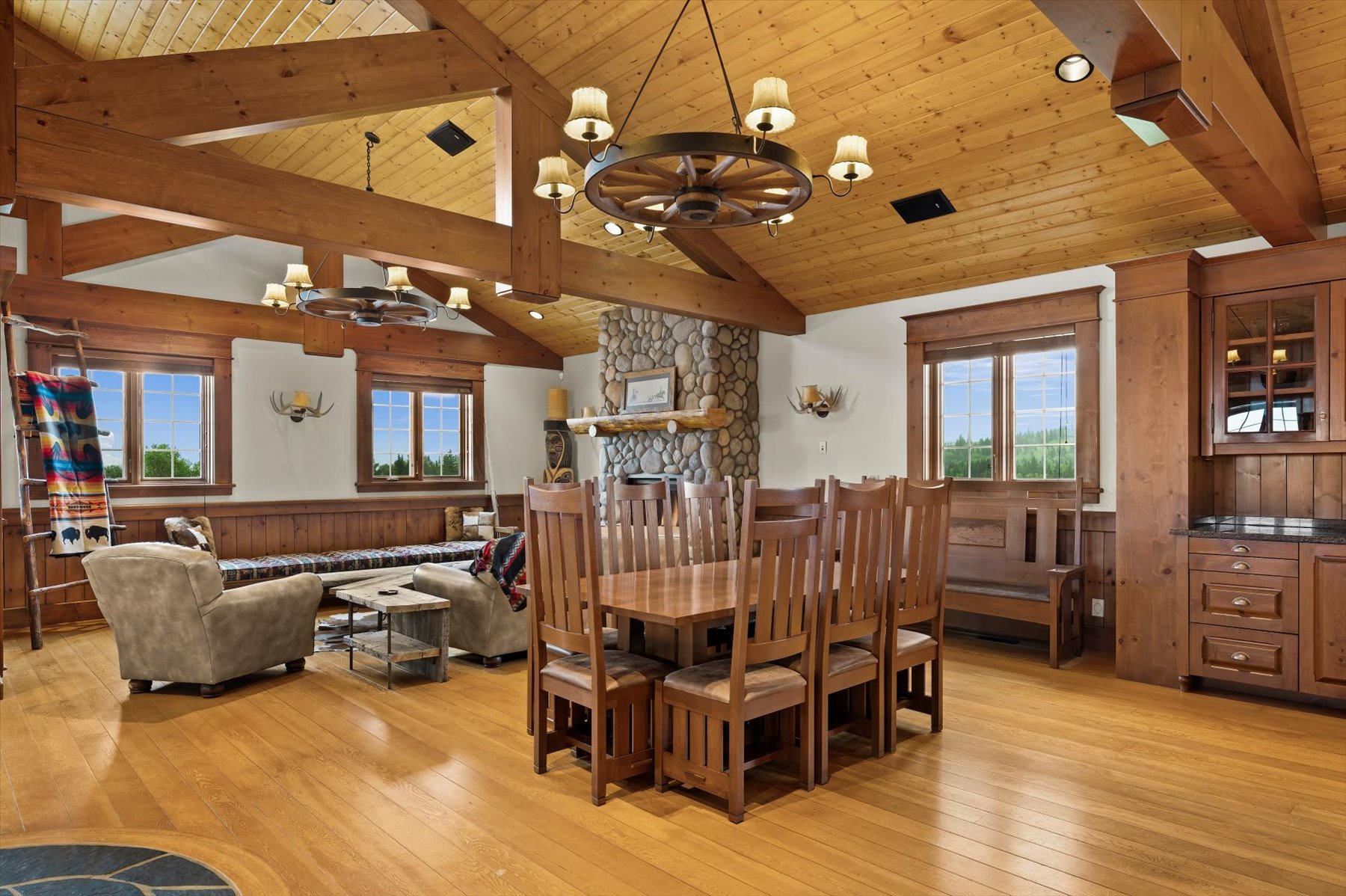 Dining table and river-rock fireplace beneath open-beam ceiling