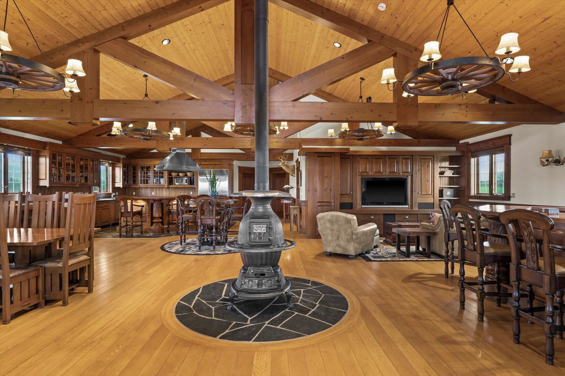 Vaulted timber-frame great room with antique pot-belly stove, open kitchen and dining
