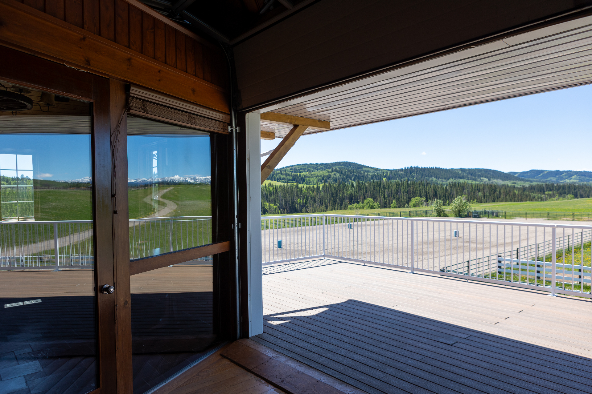 View from the covered balcony overlooking the outdoor arena with foothills beyond