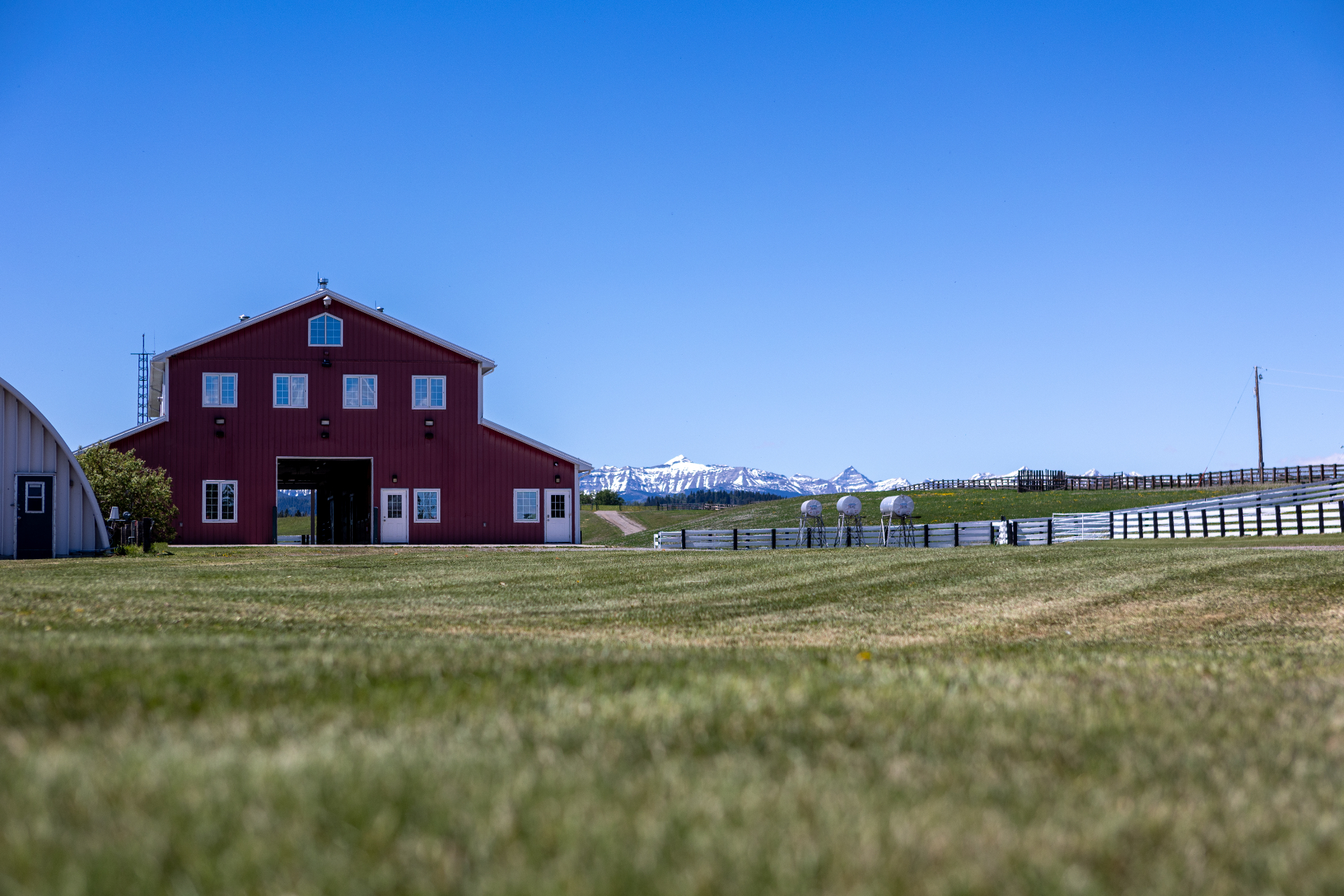 Red barn with snow-capped Rocky Mountains across the pasture