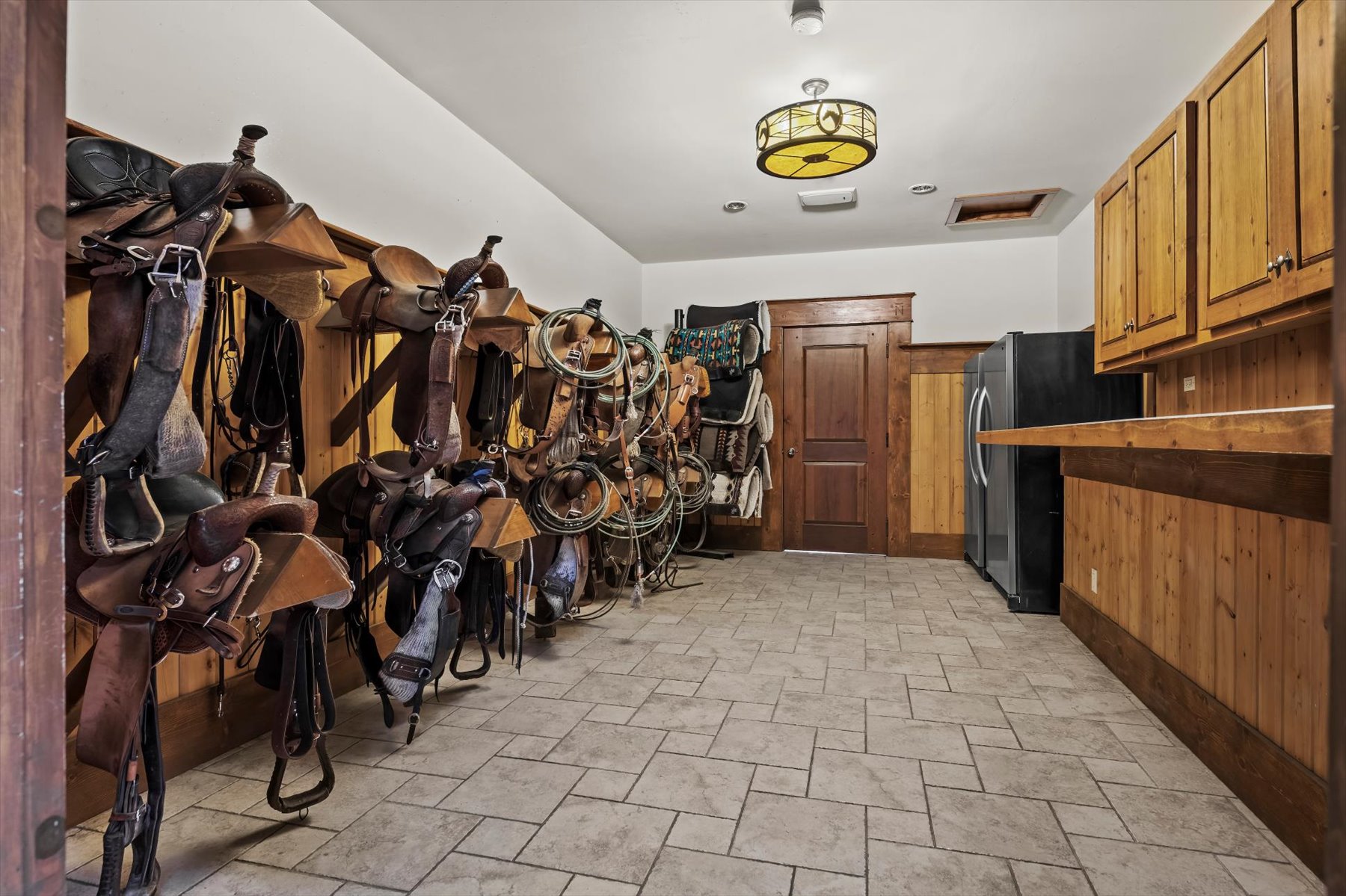 Tack room with rows of Western saddles, bridles, and ropes