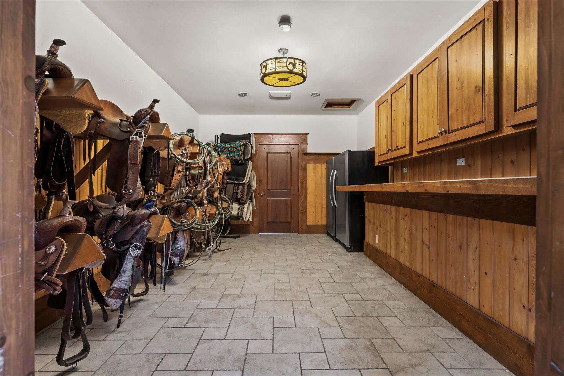 Tack room with western saddles, bridles, blankets and built-in cabinetry